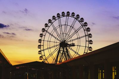 Low angle view of ferris wheel against sky at sunset