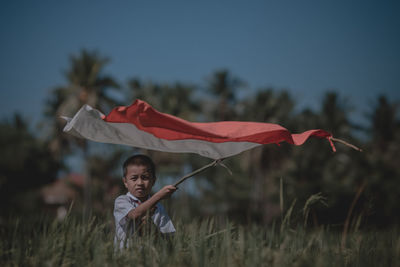 Man with indonesian flag on field against sky