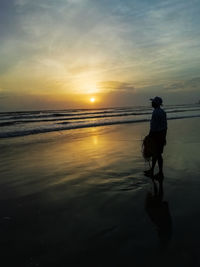 Silhouette person on beach against sky during sunset