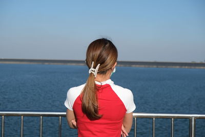 Side view of woman looking at sea against sky