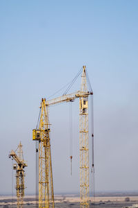 Building crane and building under construction against blue sky