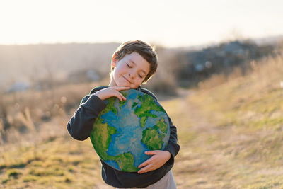 Smiling boy with eyes closed holding earth cut out