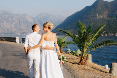 Rear view of couple standing on mountain against mountains