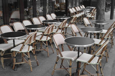 Empty chairs and tables at sidewalk cafe