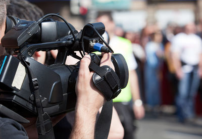 Close-up of cropped cameraman photographing crowd