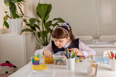 A girl pupil disassembles a box with small toys 