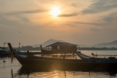 Boats moored in sea against sky during sunset