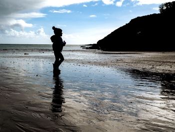 Silhouette woman standing on beach against sky