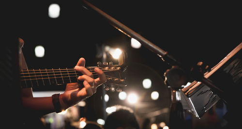 Midsection of man playing guitar at music concert