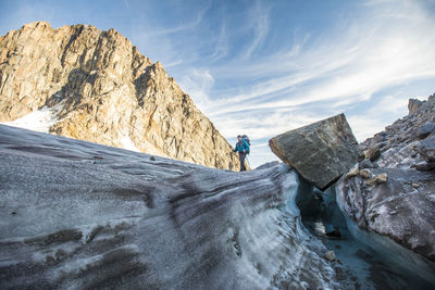 Man on rocks by mountains against sky