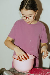 One girl bakes cookies, kneading the dough with her hands in a bowl.