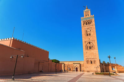 Clock tower amidst buildings against blue sky