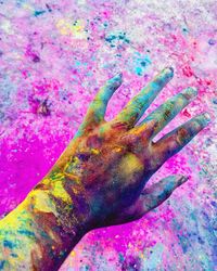 Close-up of human hand on multi colored background