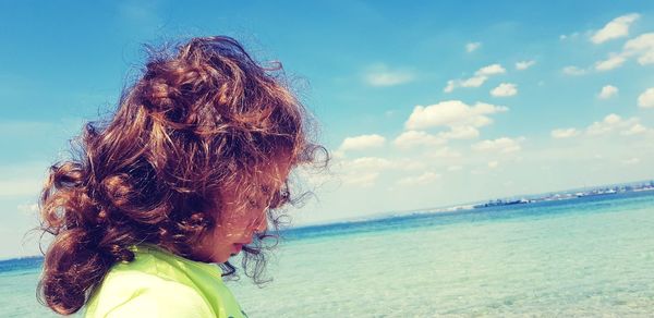 Close-up of girl by sea against sky