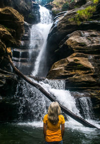 Rear view of woman standing in waterfall