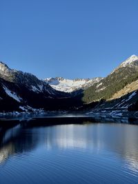 Scenic view of lake and mountains against clear blue sky