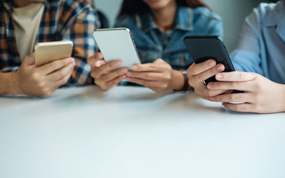 Midsection of woman using mobile phone on table