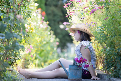 Side view of young woman sitting on plants