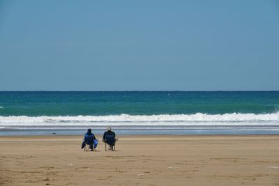 Man standing on beach against clear blue sky