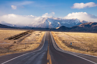 Road by snowcapped mountains against sky