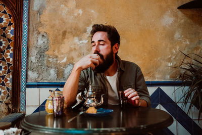 Young man looking away while sitting on table at restaurant