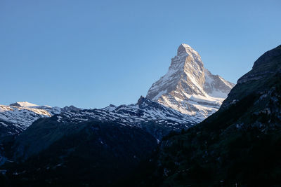 Panoramic view of snowcapped mountains against clear blue sky