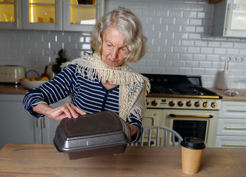 Lonely elderly woman opens food delivery from an online store