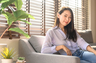 Portrait of smiling woman sitting on sofa at home