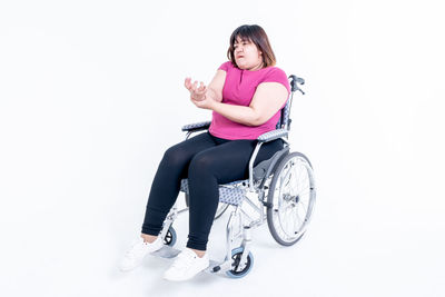 Portrait of young woman sitting against white background