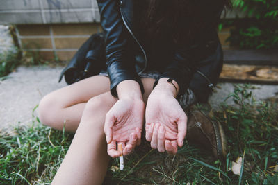 Midsection of woman showing hands while holding cigarette