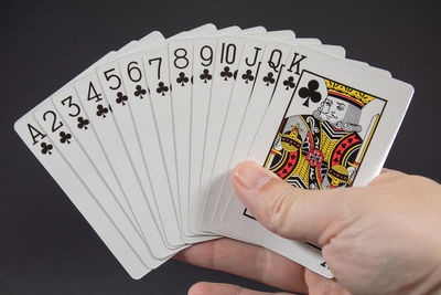 Cropped image of hand holding playing card against black background