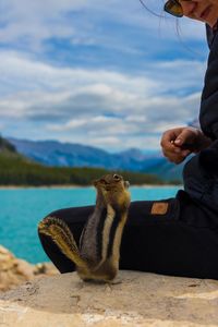 Woman sitting on hand against sky