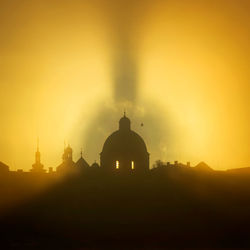 Silhouette temple against building during sunset