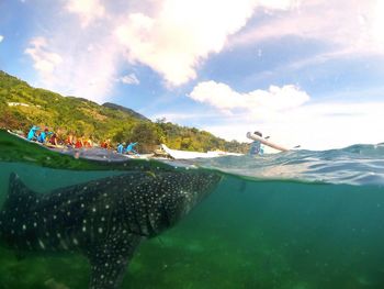 Panoramic view of people swimming in sea against sky