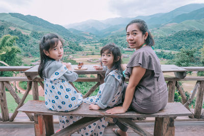 Portrait of friends sitting on railing