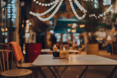 Lit up candle at an outdoor table of a restaurant in winter, cosy atmosphere, selective focus, bokeh