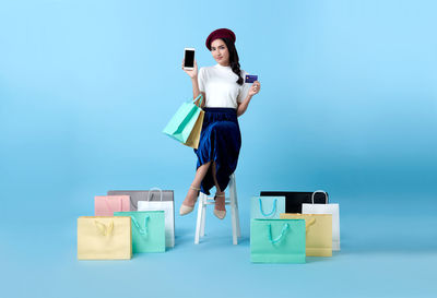 Full length of woman using smart phone against blue background