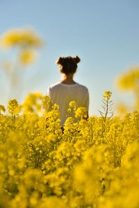 Rear view of woman standing on field against sky