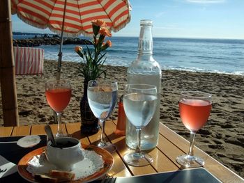 Close-up of wine glasses on table at beach against sky