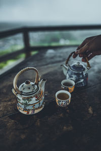 Cropped hand of person pouring tea in glass on table