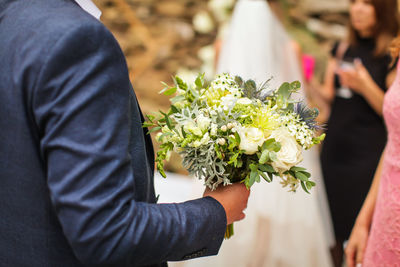 Midsection of man holding flower bouquet