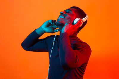 Young man looking away against orange background