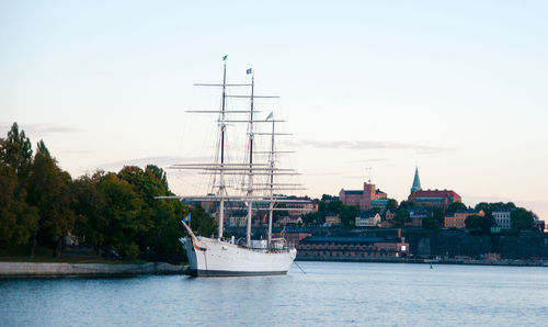 Sailboats in sea by buildings against sky