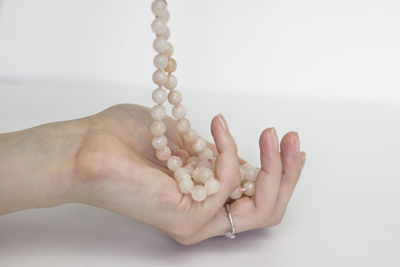 Close-up of hand holding hands over white background