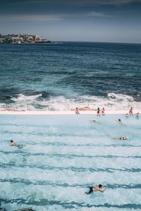 High angle view of people swimming in infinity pool against sky