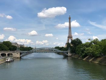Eiffel tower by river against sky