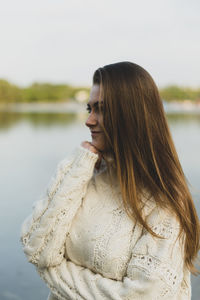 Smiling woman with long brown hair standing by lake