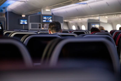 Rear view of man sitting in airplane