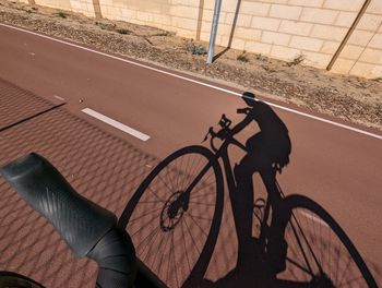 Low section of man riding bicycle on road