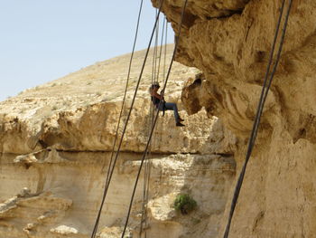 Woman climbing rock against clear sky